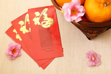 Mandarin oranges in basket with Chinese New Year red packets