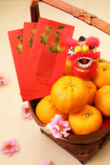 Mandarin oranges in basket with Chinese New year red packets and mini lion doll