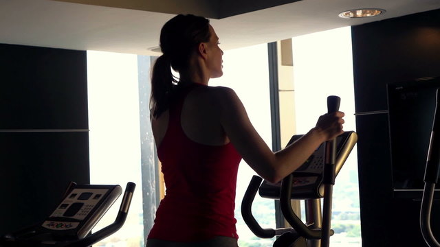 Young woman exercising on elliptical machine in gym, super slow motion 120fps
