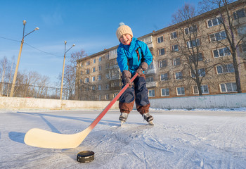 Winter time. Young boy playing ice hockey on an outdoor ice rink. 