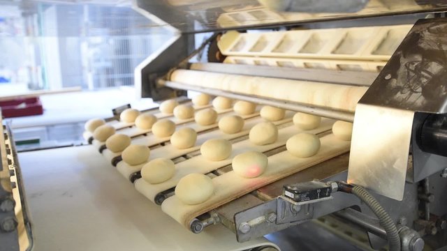 Br&ouml;tchen auf dem Fliessband einer Gro&szlig;b&auml;ckerei- industrielle Herstellung von Tiefk&uuml;hlbackwaren
