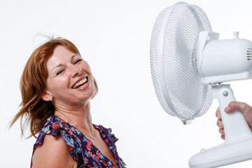 Middle-aged woman cools down with an electric fan