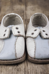 old vintage baby shoes on a wooden surface closeup