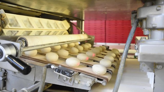 Br&ouml;tchen auf dem Fliessband einer Gro&szlig;b&auml;ckerei- industrielle Herstellung von Tiefk&uuml;hlbackwaren