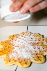 Puderzucker auf Waffel streuen