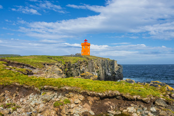 Fototapeta na wymiar Orange lighthouse at the cost of Grimsey island nearby Iceland,