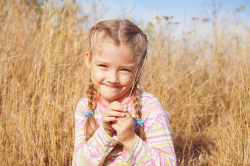 Joyful girl on nature with a blade of grass in hands