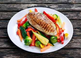 Grilled chicken fillet, breast with cooked vegetable on plates
