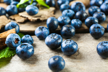 Tasty ripe blueberries with green leaves on wooden table close up