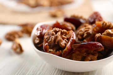 Walnut and date fruit in plate on wooden table, close-up