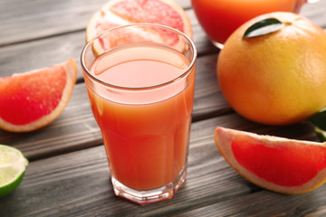 Glass of grapefruit juice and fresh fruits on wooden background