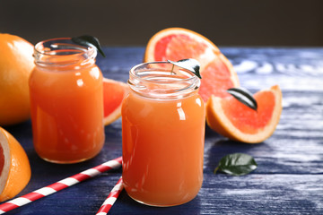 Grapefruit juice in bottles and fresh fruits on dark blue wooden background