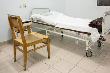 Interior of hospital room with bed and old chair