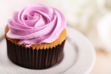 Tasty cupcake on stand, on light background