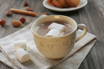 Cup of hot cacao with marshmallow on cotton serviette, close up