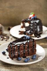 Chocolate cake with chocolate cream and fresh blueberries on plate, on wooden background