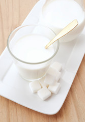 glass of milk with golden spoon and sugar cubes