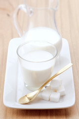 glass of milk with golden spoon and sugar cubes