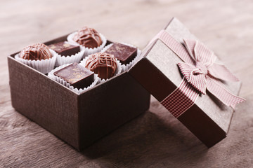 Delicious chocolate candies in beautiful gift box on wooden background