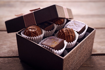 Delicious chocolate candies in beautiful gift box on wooden background