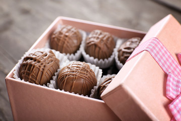 Tasty chocolate candies in pink gift box on wooden background, close up
