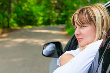 portrait of a pensive female driver 50 years looking out the win