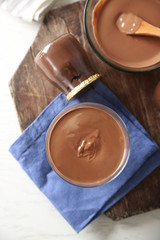 Melted chocolate in glass bowl, on wooden background