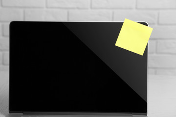 Empty yellow adhesive paper on laptop, on light background