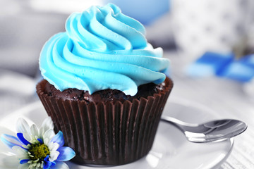 Delicious chocolate cupcake with blue cream on decorated wooden  table, close up