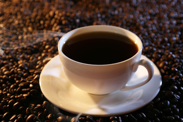 Cup of hot coffee on coffee beans background