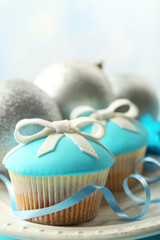 Tasty cupcakes with bow and Christmas toys on color wooden background
