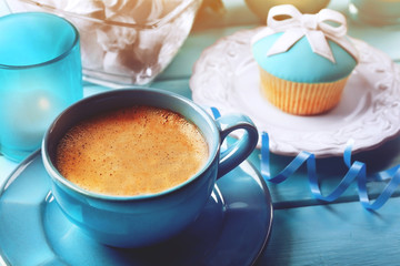 Tasty cupcake with bow, coffee cup and Christmas toys on color wooden background