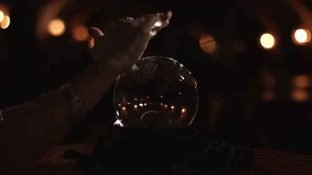Close up of a gypsy fortune teller reading a crystal ball in a stone cellar. UHD 4K.
