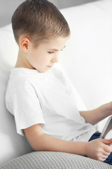 Little boy using tablet on a sofa at home