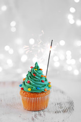 Christmas cupcake with sparkler and lights on background