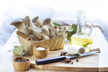 Basket with mushrooms, olive oil and ingredients for cooking on the wooden table of the kitchen background