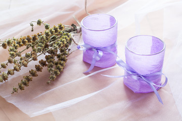 Two aromatic candles in glass candlesticks with lavender paper on table close up