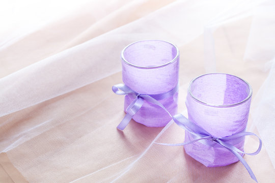 Two aromatic candles in glass candlesticks with lavender paper on table close up