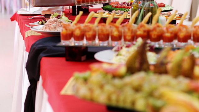 Smorgasbord table covered with colored cocktails and sweet snacks. Moving focus.