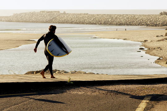 body surfer man  walking in wooden footpath to beach