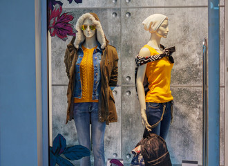 Fototapeta na wymiar Two female mannequin in warm clothes on shop window. Fashion and