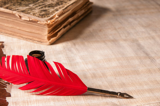 Red quill pen and black inkwell on a papyrus sheet