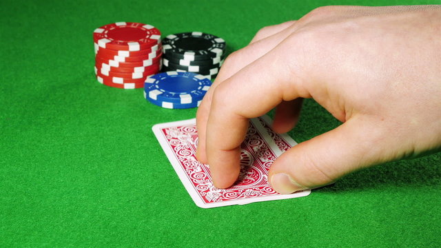 Poker player with pocket ace and king looks at his cards.