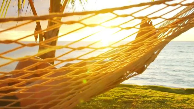 Romantic couple relaxing in tropical hammock at sunset. Summer Luxury Vacation. SLOW MOTION. 