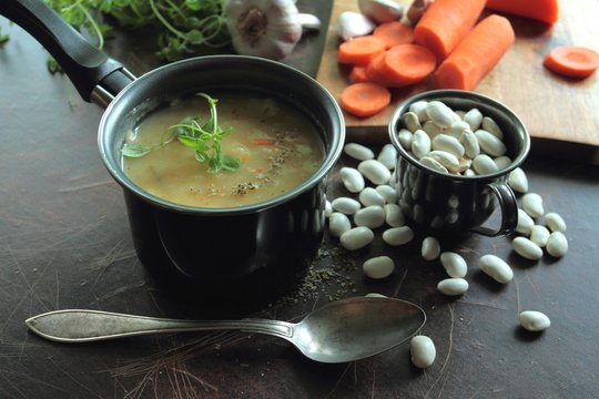 Small pot with bean soup and fresh herbs