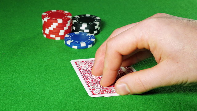 Poker player with pocket pair of queens looks at his cards.