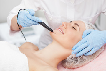 Skillful female beautician is curing her patient