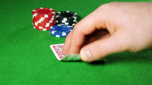 Poker player with pocket 2 and 7 looks at his cards.