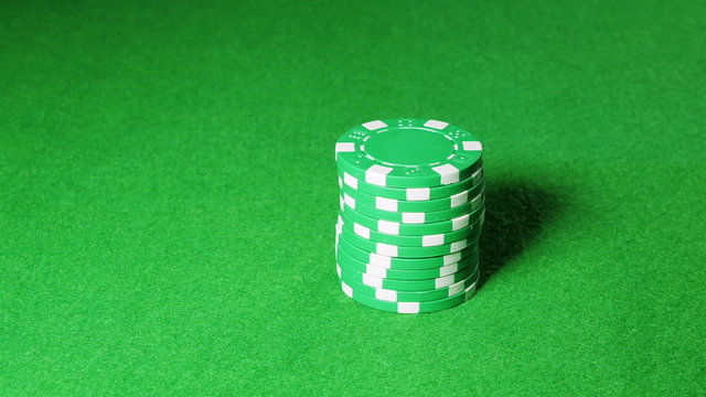 Man moves a stack of green poker chips