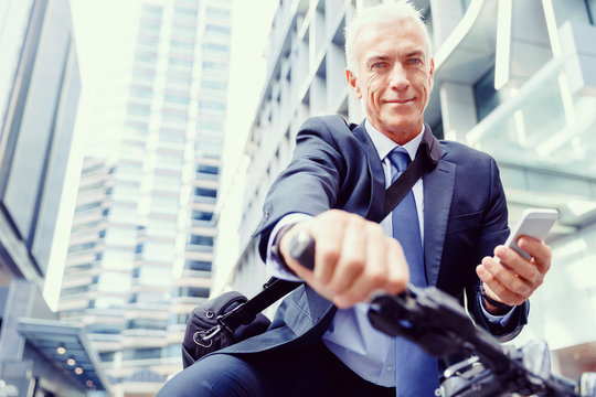 Successful businessman on bicycle with mobile phone